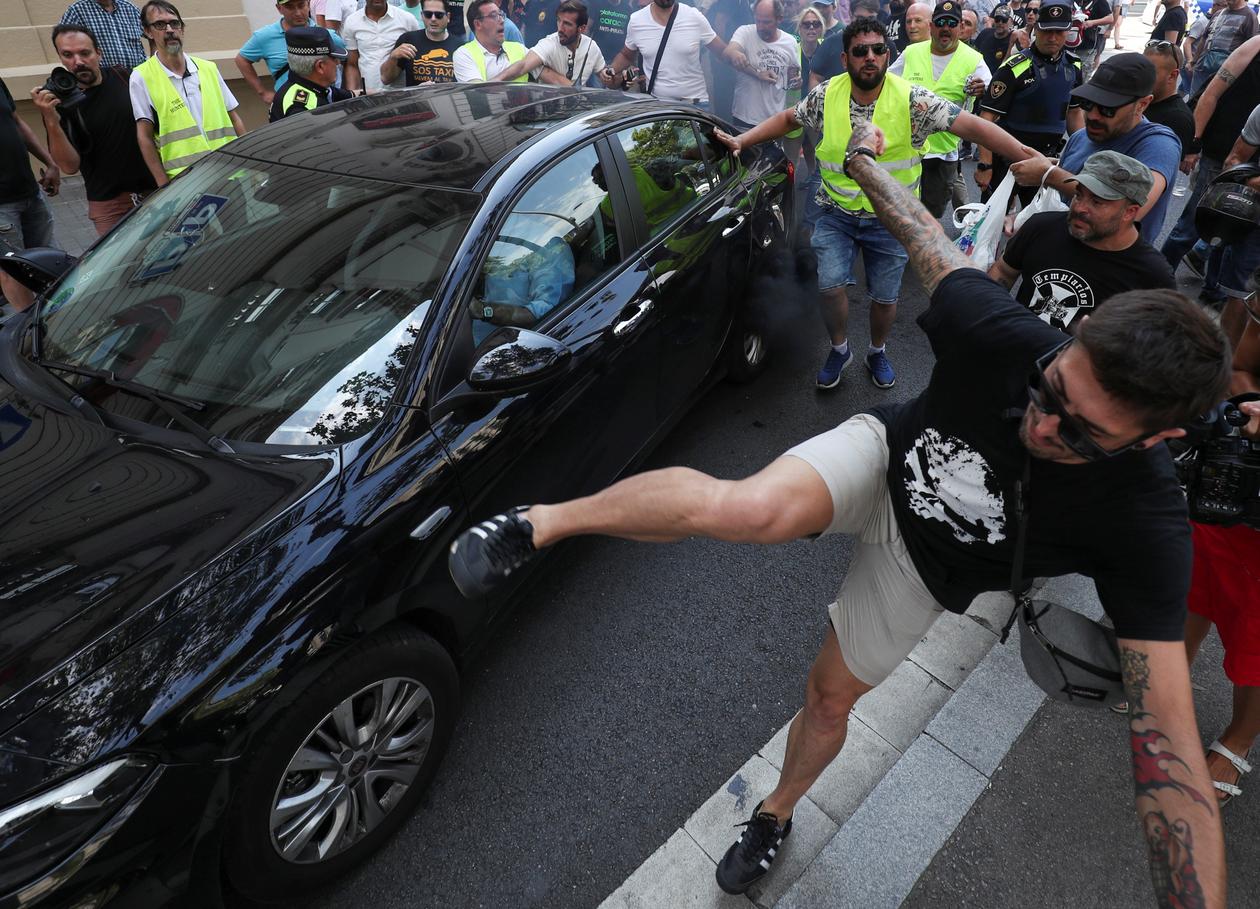 Un chauffeur de taxi s’en prend à un véhicule Uber lors d’une manifestation contre le modéle économique de la plate-forme américaine, à Barcelone (Espagne), le 25 juillet 2018.
