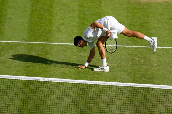 O sérvio Novak Djokovic toca o gramado do Tribunal Central de Wimbledon depois de derrotar o British Cameron Norrie nas meias-finais, em 8 de julho de 2022, em Londres.