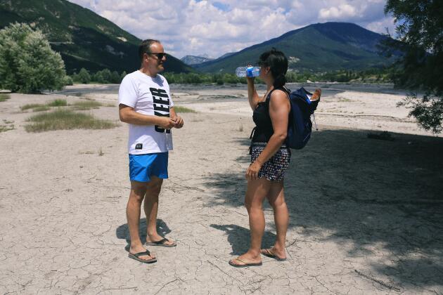 Shirley et René, des touristes hollandais, marchent sur une portion asséchée du lac de Castillon (Alpes-de-Haute-Provence), le 11 juillet 2022. 
