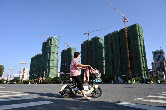 Une femme passe en scooter devant le site de construction d’un complexe immobilier Evergrande à Zhumadian, dans la province du Henan (centre de la Chine), le 14 septembre 2021.