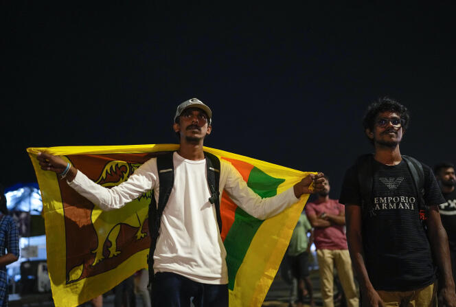 A Sri Lankan celebrates with a national flag as they react to early reports of President Gotabaya Rajapaksa's resignation in Colombo, Sri Lanka, Thursday, July 14, 2022. 