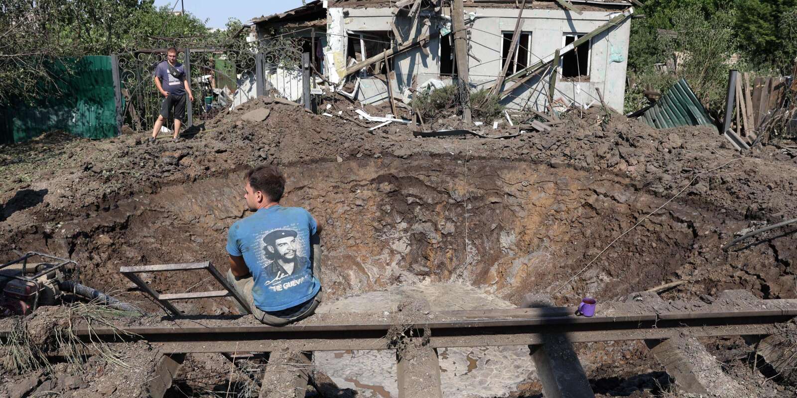 Des employés des services communaux travaillent autour d’un cratère asuite à une frappe de missile russe dans la ville de Konstantinovka, dans la région de Donetsk, le 16 juillet 2022.