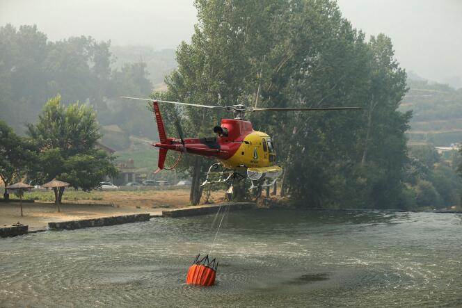 A helicopter picks up water from a dam as they work on containing a wildfire at Garganta de los Infiernos natural reserve, during the second heatwave of the year, in Jerte, Spain, July 17, 2022. 
