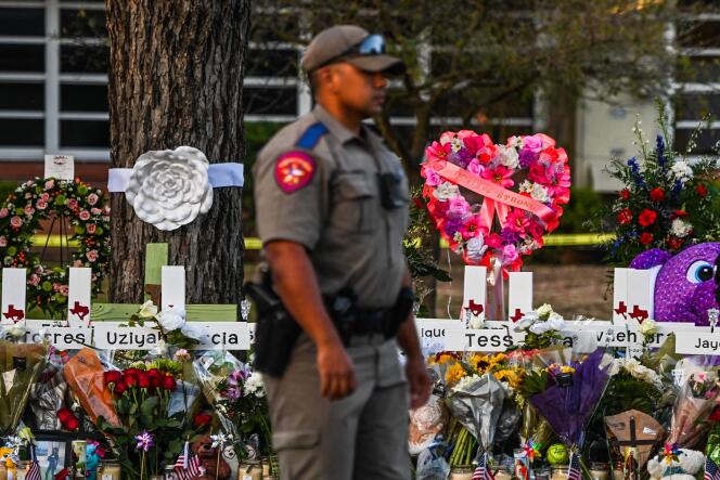 In this file photo taken on May 27, 2022, a police officer stands near a makeshift memorial for the shooting victims outside Robb Elementary School in Uvalde, Texas.