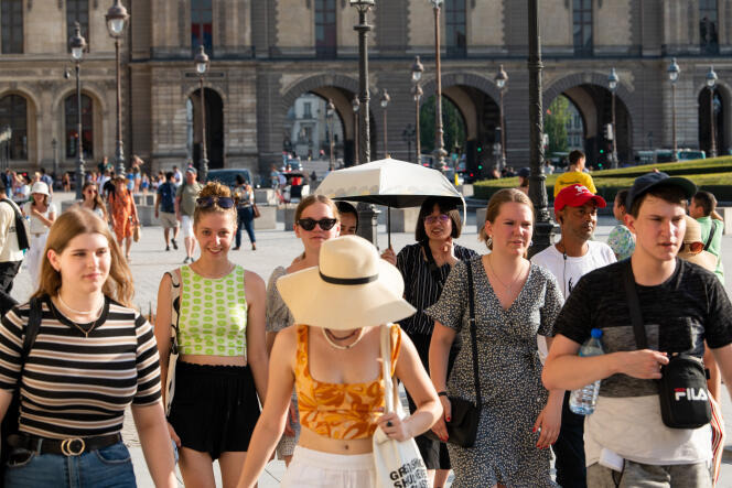 París, Francia 18 de julio de 2022: En la Place du Carrousel, cerca del Louvre, los visitantes caminan y se protegen lo mejor que pueden del sol aplastante.