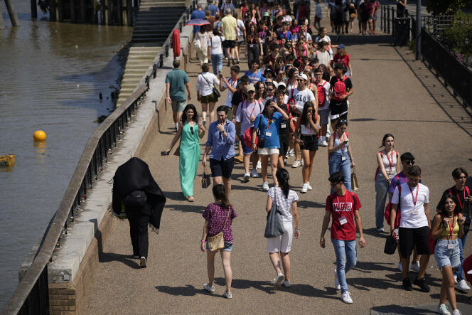 People walk by the River Thames, during hot weather in London, Monday, July 18, 2022. 