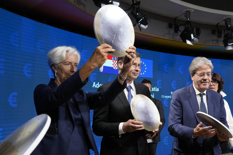 European Central Bank President Christine Lagarde, center, holds up a cardboard euro coin after a signing ceremony for Croatia to join the euro in Brussels, Tuesday, July 12, 2022. The European Union is set on Tuesday to remove the final obstacles for Croatia to adopt the euro, ensuring the first expansion of the currency bloc in almost a decade. (AP Photo/Virginia Mayo)