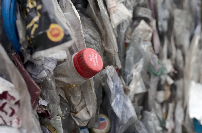 Inscription « Veuillez me recycler » sur le bouchon d’une bouteille de Coca-Cola, au milieu des balles de plastique PET triées dans l’usine de recyclage de Viridor, en Grande-Bretagne. Image extraite du documentaire « Coca-Cola, leader pollueur », de Laura Mulholland.
