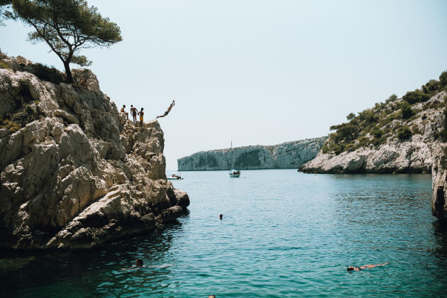 Des jeunes sautent depuis la falaise dans la calanque de Sugiton, à Marseille, le 18 juillet 2022.
