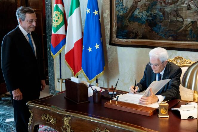 Cette photo prise et publiée le 21 juillet 2022 par le service de presse du palais présidentiel du Quirinal montre le président italien Sergio Mattarella signant le décret de dissolution du Parlement devant le premier ministre italien démissionnaire Mario Draghi.