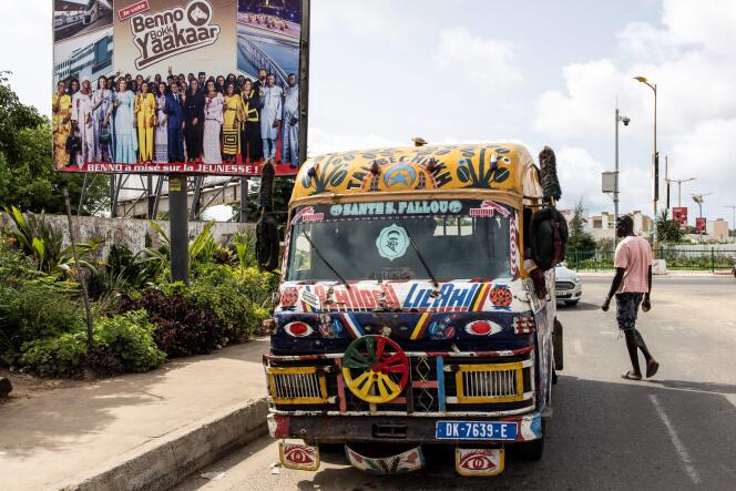 Un minibus devant une affiche du parti au pouvoir, Benno Bokk Yaakaar, à Dakar, le 27 juillet 2022.