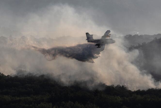 Un Canadair de seguridad civil, responsable de combatir incendios, arroja agua sobre bosques en llamas cerca de Vogüé, 27 de julio de 2022. 