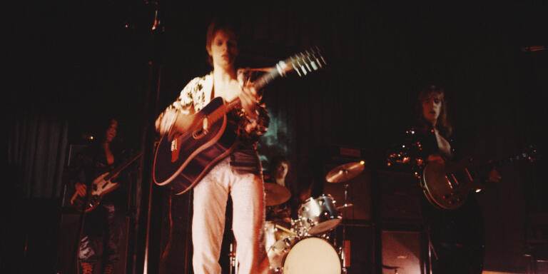 David Bowie (1947-2016) performs live on stage with his backing group The Spiders From Mars on the first night of the Ziggy Stardust Tour at Borough Assembly Hall in Aylesbury, Buckinghamshire on 29th January 1972. The band are, from left, Trevor Bolder, David Bowie, Mick 'Woody' Woodmansey and Mick Ronson (Photo by Michael Putland/Getty Images)