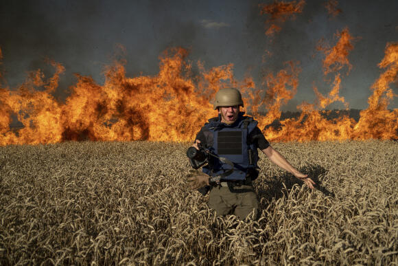 Le photojournaliste Evgeniy Maloletka s’enfuit d’un champ enflammé par un bombardement de l’armée russe, dans la région de Kharkiv, le 29 juillet 2022.