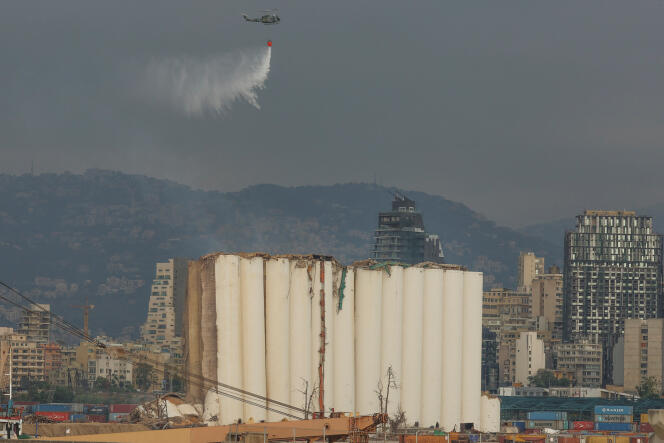 A helicopter sprays partially collapsed grain silos at the port of Beirut on Sunday, July 31, 2022.