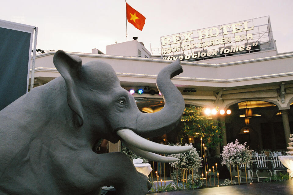 Close-up of the statue of an elephant placed on both sides of the outdoor stage at Rooftop Garden Bar, behind is the Vietnamese flag placed on the top of the Rex hotel in Ho Chi Minh City on June 27, 2022.
