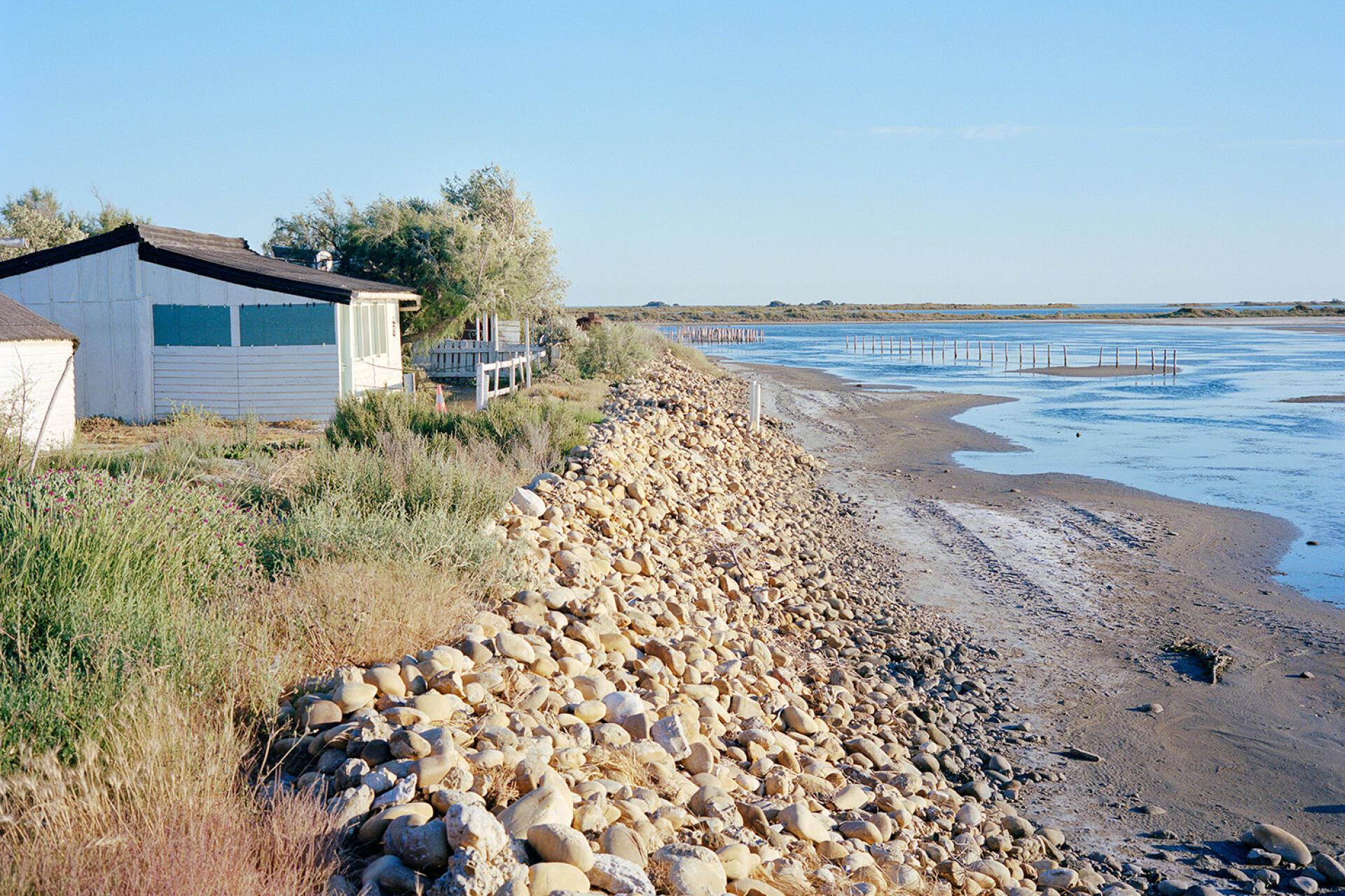 Cabins overlook the seawall built by the inhabitants, in Beauduc, Camargue, in June 2022.