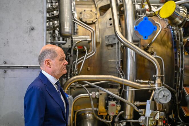 German Chancellor Olaf Scholz stands in front of a turbine of the Nord Stream 1 pipeline during a visit on August 3, 2022 at the plant of Siemens Energy in Muelheim an der Ruhr, western Germany, where the engine is stored after maintenance work in Canada. 