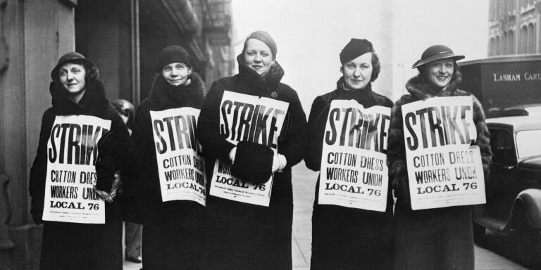 All cotton goods factories and shops workers in Chicago have been called on strike by the International Ladies' Garment Workers' Union, which claims a membership of 10,000 in the city, for higher wages and a $16 minimum. Pickets are shown above in front of a factory on market street, on the edge of downtown Chicago.