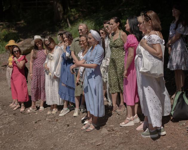 Irina, ubrana na niebiesko, prowadzi sesję medytacyjną w ramach rekolekcji dla kobiet w jeziorze Senvir na Ukrainie, 25 lipca 2022 r.