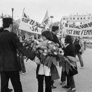 A police officer tries to drive back a dozen women participating in a demonstration, with banners and sheaves, proclaiming in particular 