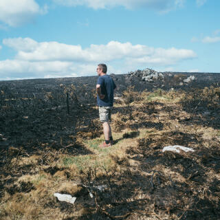 Sylvain le Treust, agriculteur en élevage bovin et équin, observe le paysage transformé suite au récent incendie, à Saint-Rivoal, finistère ( 29 ), le 21 juillet 2022.