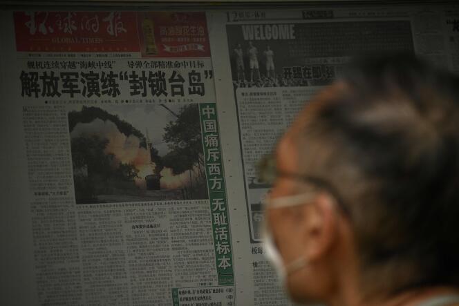 Un homme lit un journal sur les exercices militaires de la Chine encerclant Taïwan, dans une rue de Pékin, le 8 août 2022.