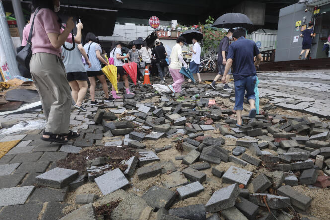 Los residentes de Seúl caminan en una sección dañada de la carretera cerca de una estación de metro en Seúl el martes 9 de agosto de 2022. 