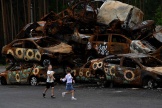 Des enfants jouent devant des voitures détruites par les troupes russes, à Irpine, près de Kiev, le 9 août 2022.