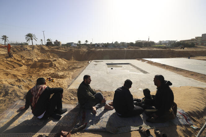 Workers take a break as Egyptian machinery works at the construction site of a new housing complex, north of Gaza City, January 11, 2022. 