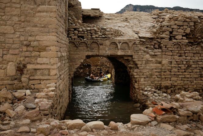 People paddle a kayak past the remains of the church of Sant Roma de Sau as it emerges from the low waters of the Sau Reservoir, north of Barcelona, Spain, August 8, 2022.  
