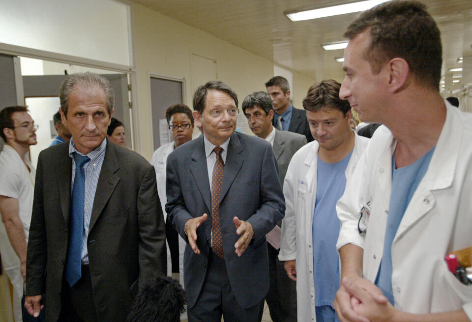le ministre de la Santé Jean-François Mattei (C) et le secrétaire d'Etat aux personnes âgées Hubert Falco (G) visitent le service des urgences de l'Hôpital de la Pitié-Salpêtrière, le 13 août 2003 à Paris, alors que la majorité des hôpitaux sont débordés par l'afflux de patients du fait de la canicule. (Photo by THOMAS COEX / AFP)