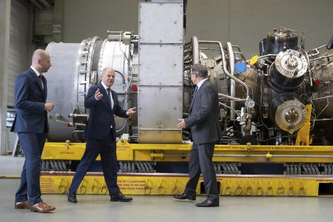 Le chancelier allemand, Olaf Scholz (au centre), et le PDG de Siemens Energy, Christian Bruch (à gauche), près d’une turbine destinée au pipeline Nordstream 1, à Mülheim (Allemagne), le 3 août 2022. 