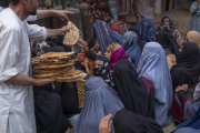 Bread donated by other customers is distributed to women and children begging in front of a bakery in Kabul on August 4