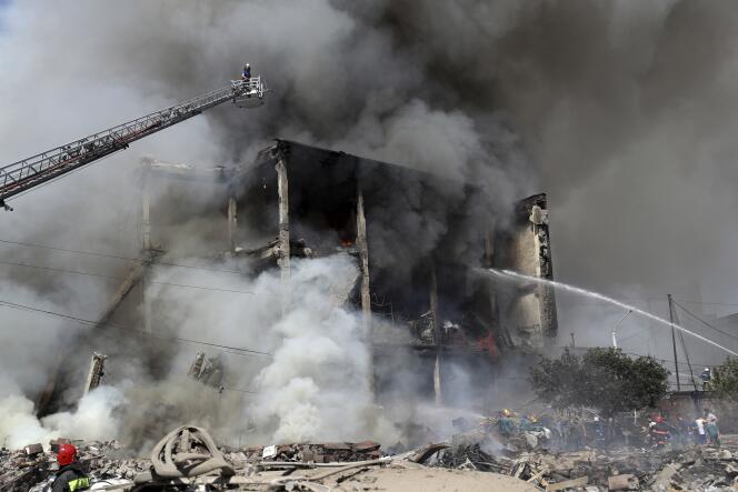 Feuerwehrleute entfernen schwelende Trümmer von der Fassade eines Gebäudes, das nach einer Explosion am 14. August 2022 in Jerewan durch Feuer geschwärzt war.