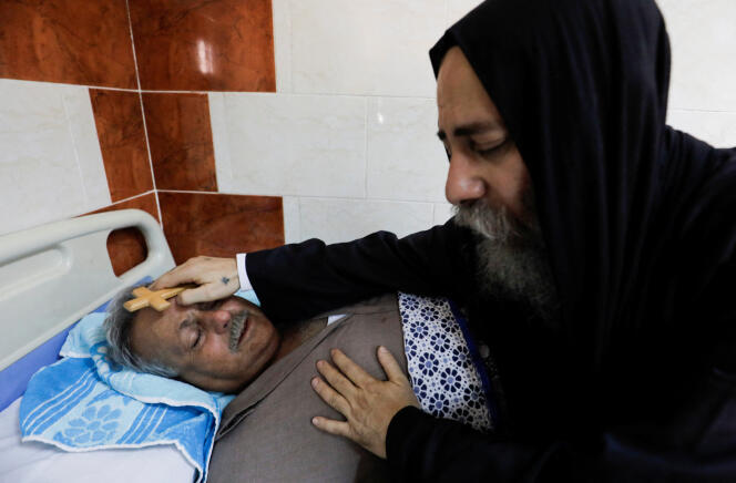 Un prêtre copte bénit une victime de l’incendie meurtrier qui a éclaté à l’église Abou Sifin, dans un hôpital de Gizeh, en Egypte, le 14 août 2022. 