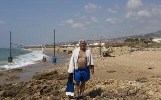 Jamal Haidous stands on rocks at a public beach in Damour, south of Beirut, Lebanon, Saturday, July 30, 2022.