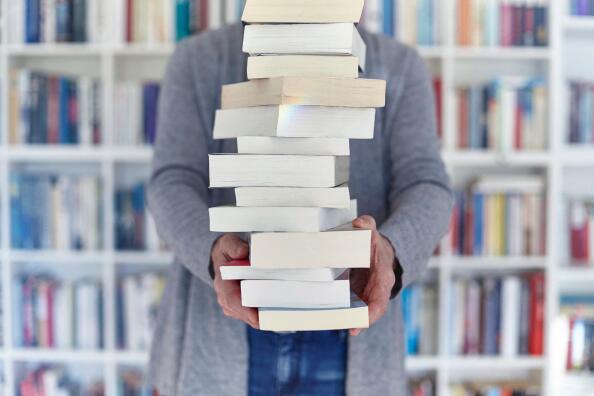 Woman holding stack of books, mid section