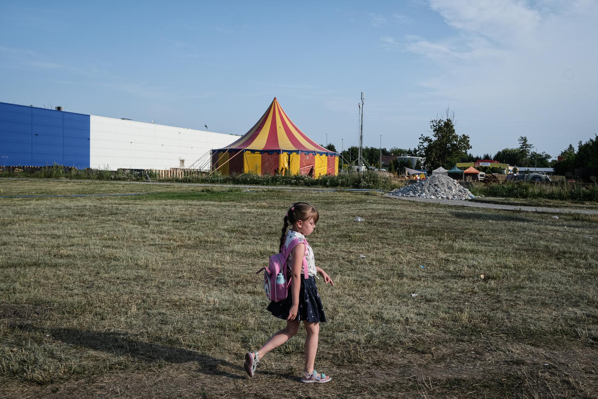 Siedmioletnia córka Ivany Ivchenko, Sophia, przechodzi obok byłego supermarketu Tesco, w którym ukraińscy uchodźcy i jej matka pracują w Przemyślu, 22 lipca 2022 roku.