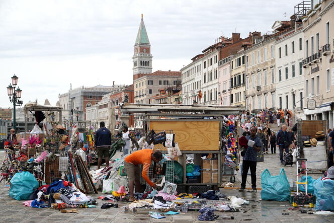 Sur les quais de la place Saint-Marc, à Venise (Italie), des vendeurs ramassent les marchandises des étals endommagés par la tempête qui a frappé le nord de la péninsule, le 18 août 2022.  