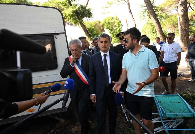 Gérald Darmanin et le maire de Calvi, Ange Santini (à gauche), écoutent les témoignages de touristes victimes de violents orages, alors qu’ils visitent le camping de La Pinède, à Calvi, en Corse, le 19 août 2022.