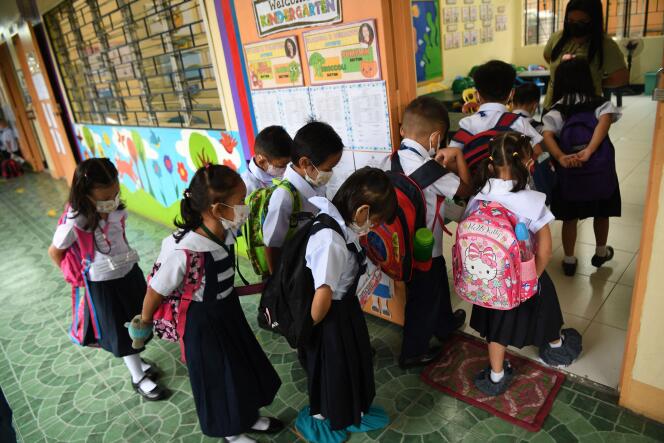 Des élèves portant des masques entrent dans leur classe pour la reprise des cours en présentiel aux Philippines, dans une école de Quezon City, dans la banlieue de Manille, le 22 août 2022.