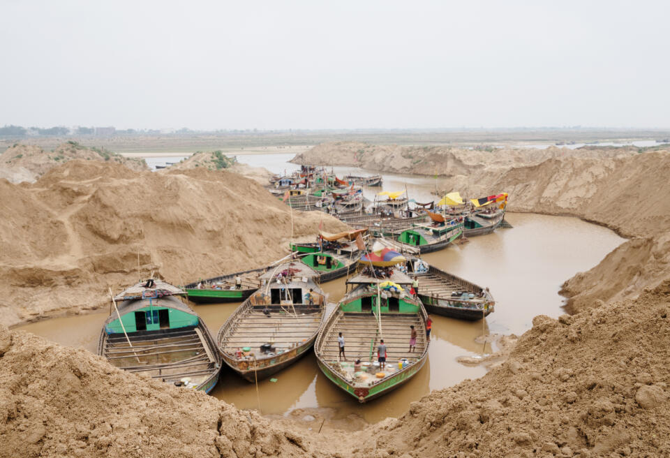 Des hommes attendent parfois depuis l’aube l'arrivée des caterpillars pour amasser le « pila sona » – l’« or jaune » : le sable de ce cours d’eau, l’un des principaux affluents du Gange, est réputé pour être d’excellente qualité. Sur une distance de 5-6 km il y a des centaines de bateaux qui attendent d'être remplies. Du 1er juin au 30 septembre, l'Etat du Bihar impose une interdiction d’extraction du sable aux seins de ces rivières. Au-dessus de leurs têtes, la rive plonge à pic sur une vingtaine de mètres. Pour 400 roupies (5 euros) par jour, ils s’éreintent au pied de cette falaise de sable qui risque à tout moment de les ensevelir, sous la surveillance de jeunes hommes contrôlant la zone. L’Etat rural du Bihar, situé dans l’est de l’Inde, est l’un des plus pauvres et des plus densément peuplés. Comme dans le reste du pays, la très forte croissance démographique entraîne un boom de la construction, qui génère à son tour une explosion de la demande en sable. L’Inde est le deuxième producteur mondial de ciment (330 millions de tonnes en 2021, contre 260 millions en 2014) derrière la Chine, et prendra dès l’an prochain la première place en termes de nombre d’habitants (plus d’1,4 milliard). Rivière Son, Inde 2022