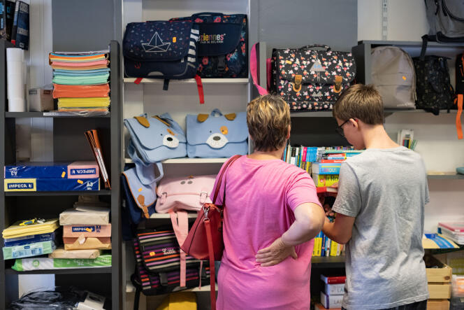 Linda (left) and her son Lucas, who is entering third grade, are looking for school supplies, during a sale organized by Emmaüs Pablo-Picasso, in Nanterre, August 23, 2022. 