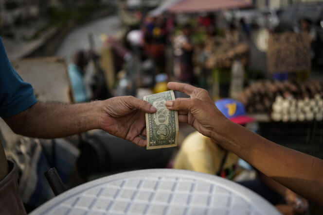 Yanosky Roo gets a dollar from a customer after selling a glass of hot oatmeal in the Quinta Crespo neighborhood of Caracas, Venezuela. August 27, 2022.
