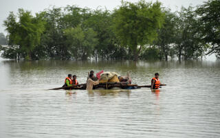 Displaced people transport usable belongings salvaged from their flood-hit home as they cross a flooded area in Sohbat Pur city of Jaffarabad, a district of Pakistan's southwestern Baluchistan province, Sunday, Aug. 28, 2022. Officials in Pakistan say deaths from widespread flooding have topped 1,000 since mid-June. (AP Photo/Zahid Hussain)