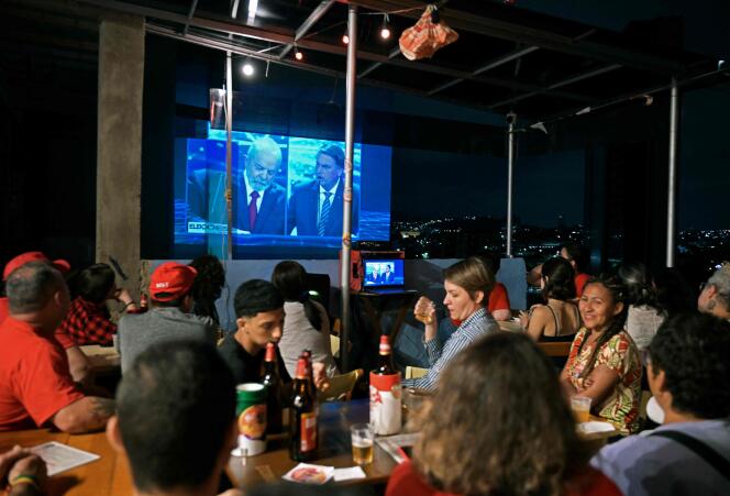 The debate between the presidential candidates in Brazil is projected on a wall near a bar in Rio de Janeiro, August 28, 2022.