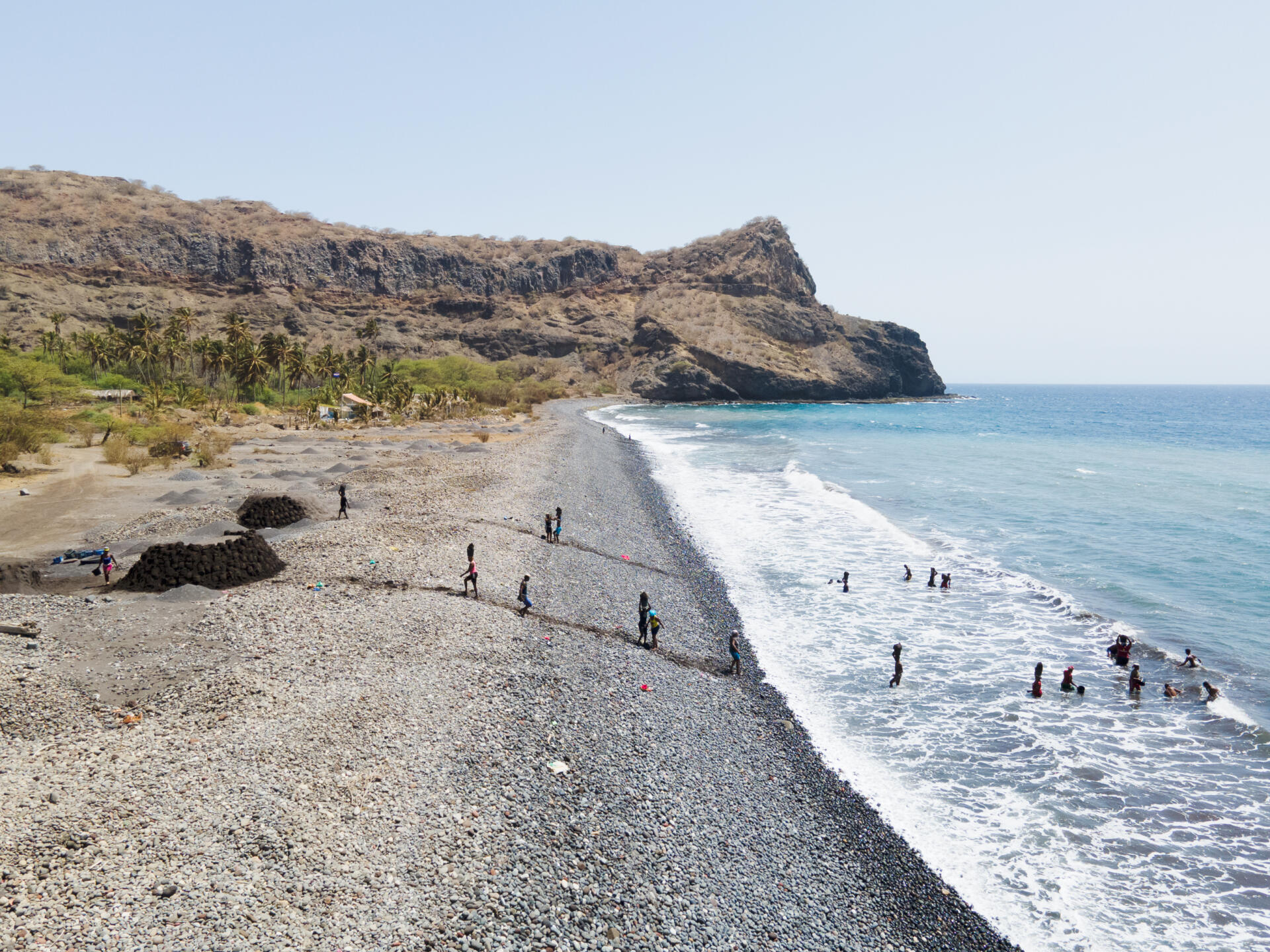 Des femmes font des aller-retour incessants entre la mer et la plage pour y ramasser et transporter du sable, sur la plage de Ribeira da Barca, sur l’île de Santiago (Cap-Vert), en juin 2022.