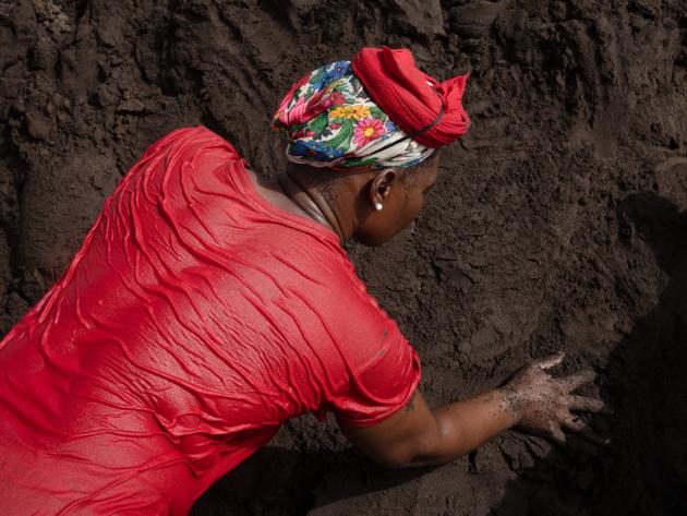 De gros talus sont formés sur la plage, le sable est humidifié et tassé pour qu’il ne s’envole pas. Sur la tête de cette femme, l’« ordidja », qui permet de caler les charges sur la tête. A Ribeira da Barca (Cap-Vert), le 15 juin 2022.