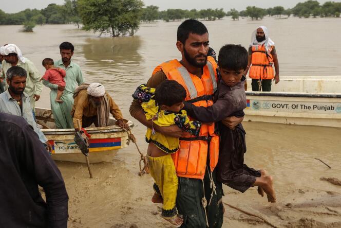 Des secouristes aident à évacuer les personnes touchées par les inondations de leurs maisons après les fortes pluies de mousson dans le district de Rajanpur, dans la province du Punjab, le 27 août 2022.  